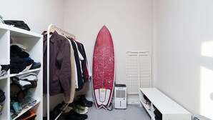 A compact room with a white wardrobe, a surfboard leaning against the wall, and a heater. - Charming 1-bedroom Flat in London (London)