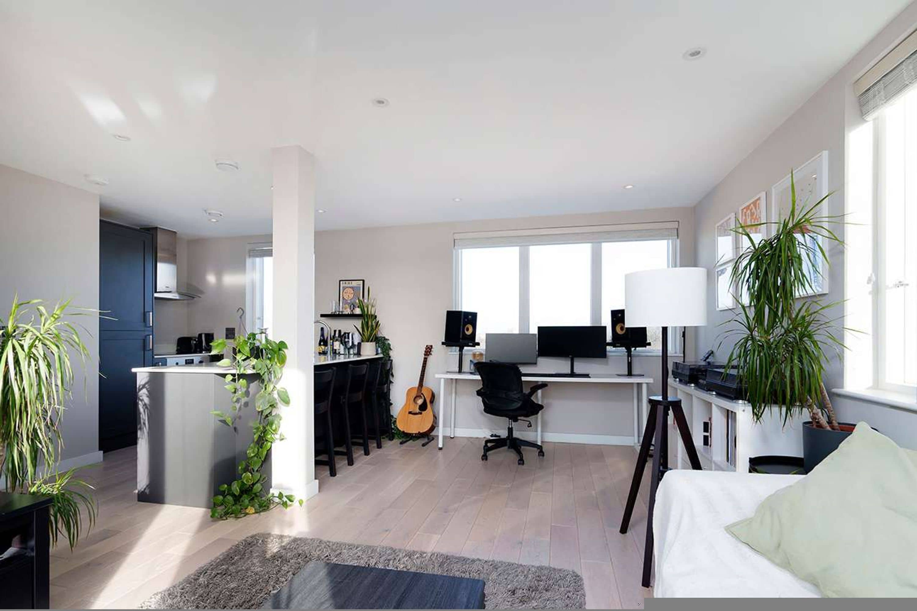 A modern, open-plan living space with a kitchen, dining area, and workspace.