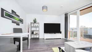 A modern living room with a flat-screen TV, a dining table, and a sofa. - Stunning 2BR Flat With Balcony (Maidenhead)