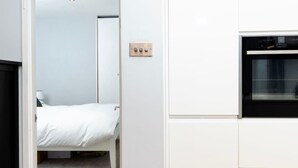 A compact room with a bed, a white wardrobe, and a built-in oven. - Charming Ground Floor Flat in Twickenham (Twickenham)