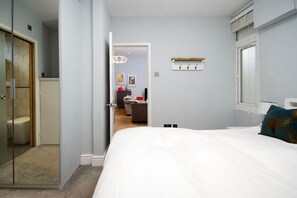 Ein Schlafzimmer mit einem Bett, einem Nachttisch, einem Spiegel und einer Tür zu einem Badezimmer.