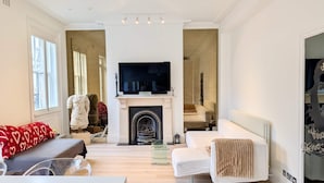 A modern living room with a fireplace, a television, and a sofa. - Stylish 1 Bed in SW7 With Private Balcony (London)