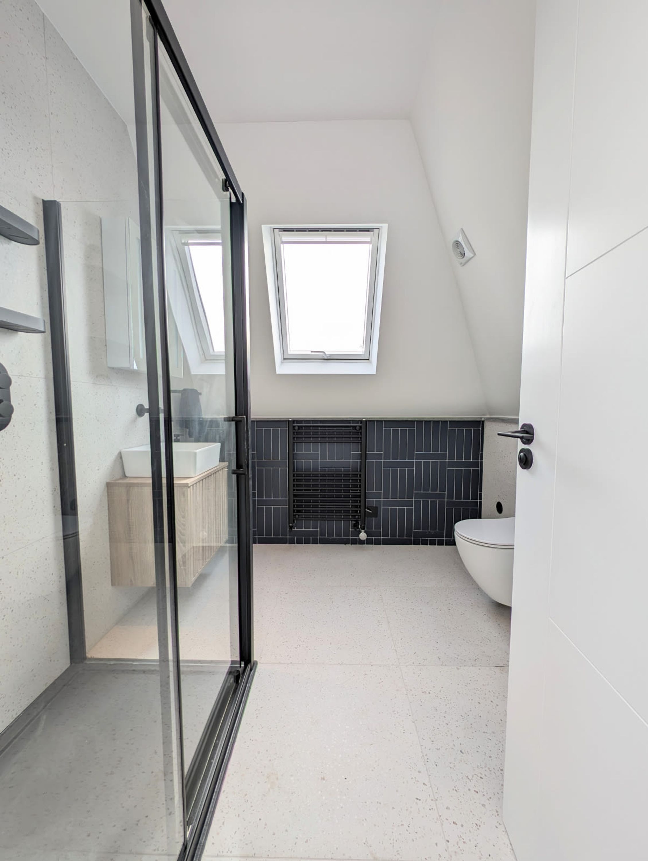 Een moderne badkamer met dakraam, een vrijstaand bad en een grote spiegel.