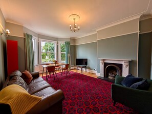 A living room with a fireplace, a sofa, a TV, and a dining area with a table and chairs. - Charming Two-bedroom House in London (Pinner)