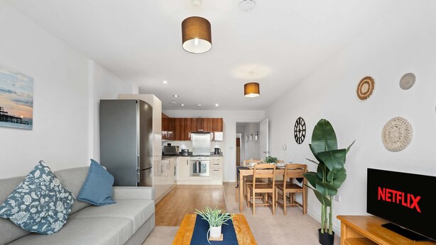 Una sala de estar moderna con un sofá, una mesa de centro, un televisor y un comedor con una mesa de madera y sillas.