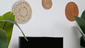 Un mueble bajo de madera para televisor con un televisor de pantalla plana que muestra la palabra "NETFLIX" en letras rojas.