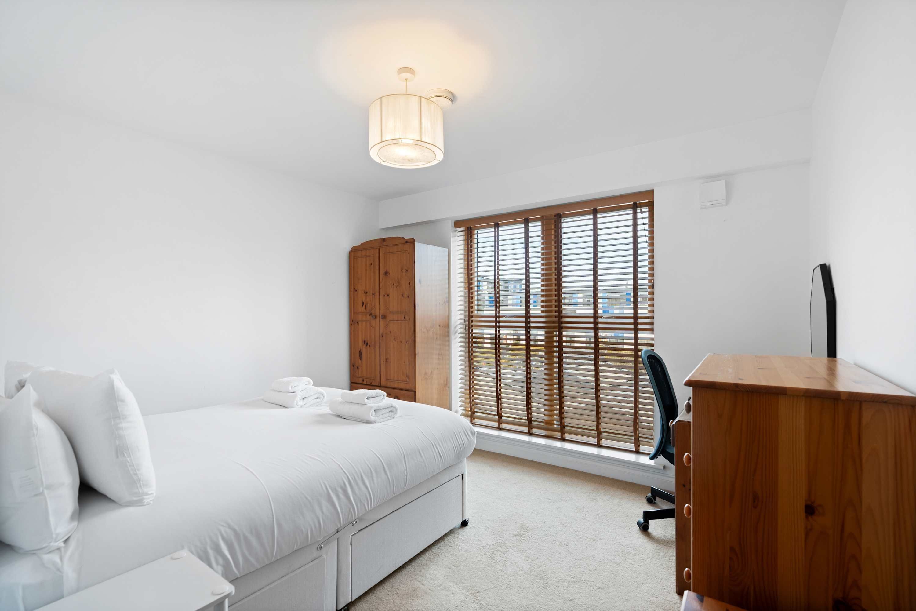 Ein Schlafzimmer mit Bett, Holzschrank und Schreibtisch.
