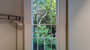 A room with a large window divided into nine panes, offering a view of dense foliage outside. - Elegant 2-bed Flat in Shenfield (Brentwood)