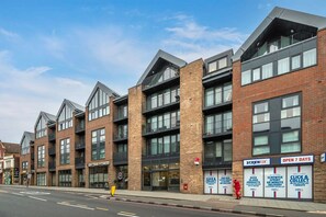 A modern building with multiple floors, featuring a brick facade and large windows. - Modern Urban Apartment in London (London)