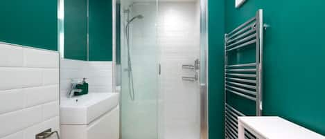 A modern bathroom with a glass-enclosed shower, white sink, and a towel rack.
