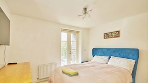 A bedroom with a bed, a wooden desk, a radiator, and a window.