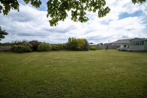 A grassy yard with a small shed and a chair. - Spacious Home Near Porthtowan Beach (Truro)