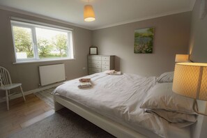 A bedroom with a bed, a dresser, a chair, a window, and a lamp. - Spacious Home Near Porthtowan Beach (Truro)