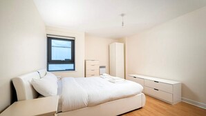 Une chambre moderne avec un grand lit, des tables de chevet, une armoire et une fenêtre.