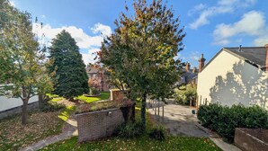 A residential area with a grassy lawn, a brick wall, and a tree. - Charming Flat With Free Parking in Prime Location (Royal Tunbridge Wells)