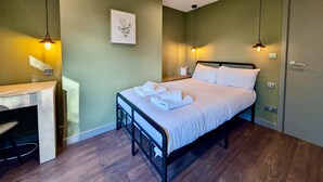 A neatly arranged bedroom with a bed, bedside tables, and a desk. - Charming Flat With Free Parking in Prime Location (Royal Tunbridge Wells)