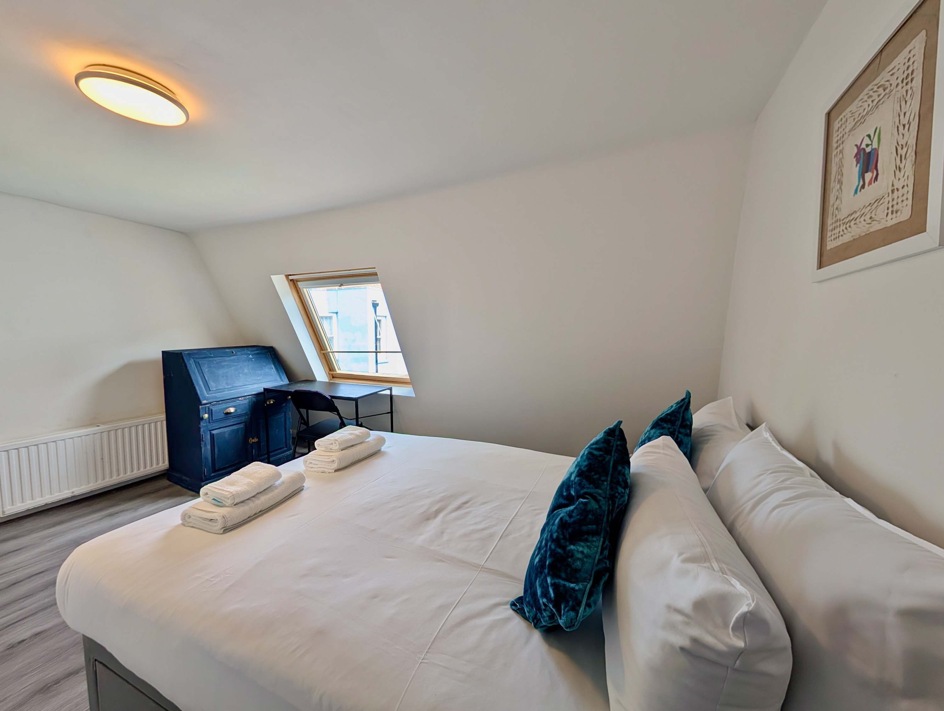 Ein Hotelzimmer mit Bett, Schreibtisch, Stuhl und Fenster.