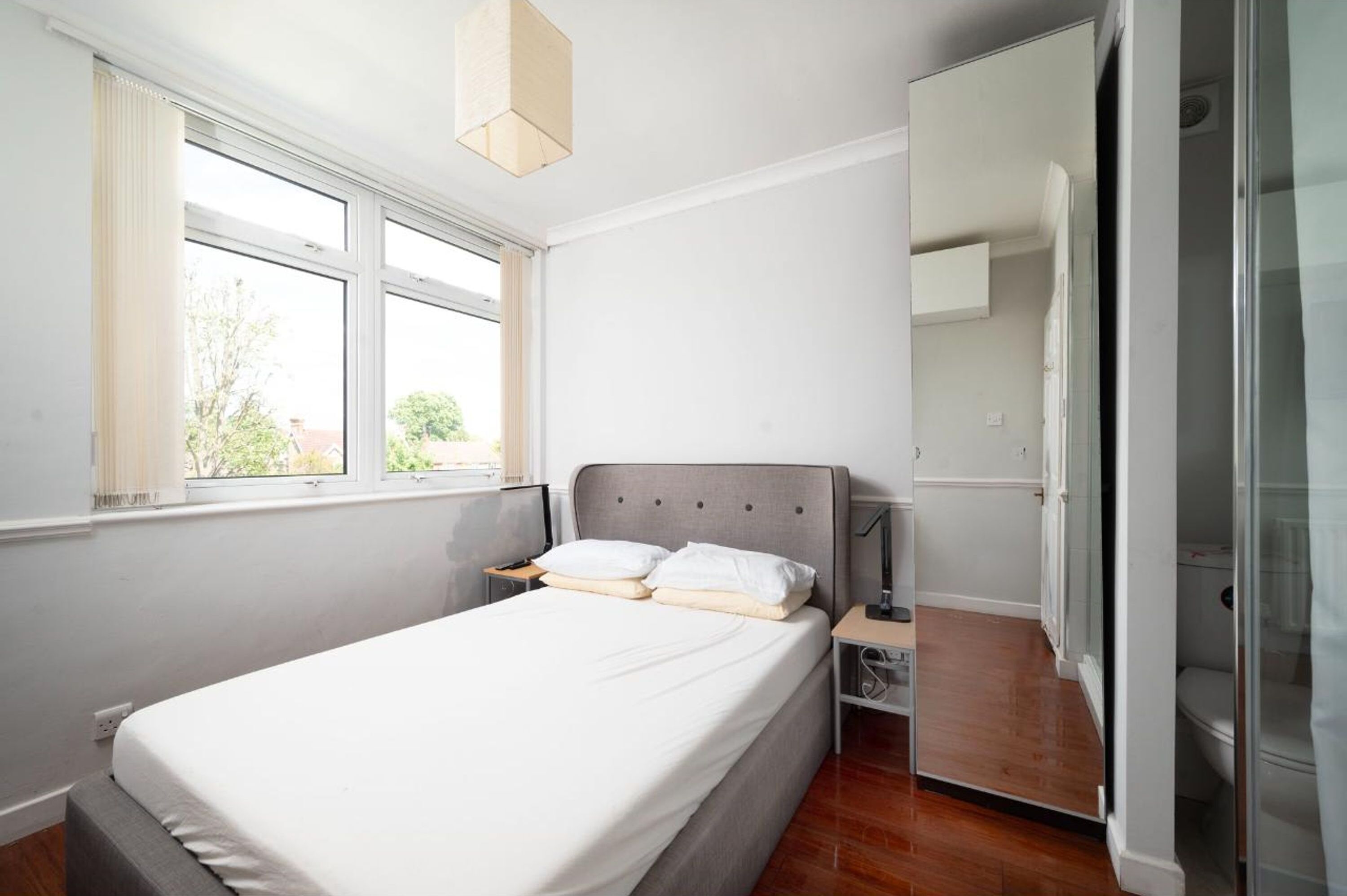 A bedroom with a bed, bedside table, and a wardrobe.