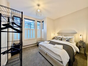 A bedroom with a bed, a radiator, a window, and a hanging light fixture. - Stylish 2 Bed Clapham Flat With Private Patio (London)