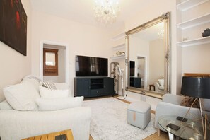 A modern living room with a large mirror, a flat-screen TV, and a comfortable seating area. - Charming Victorian Home in Westminster (London)