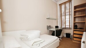 Een keurig opgeruimde slaapkamer met een bed, een bureau en een plankunit.