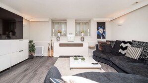 A modern living room with a grey sofa, a white coffee table, and a fireplace. - Luxury Chelsea Flat Near Museums (London)