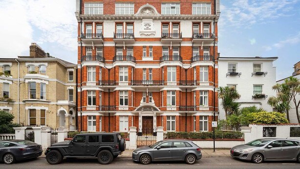 A multi-story red-brick building with a central entrance, balconies, and a sign indicating it is a hotel. - Luxury Chelsea Flat Near Museums (London)