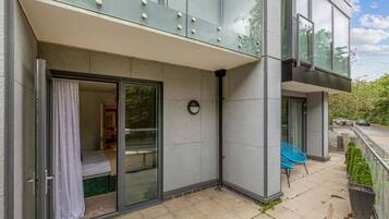 A modern building with a glass door entrance, a small balcony with a chair, and a clear view of the surrounding area.