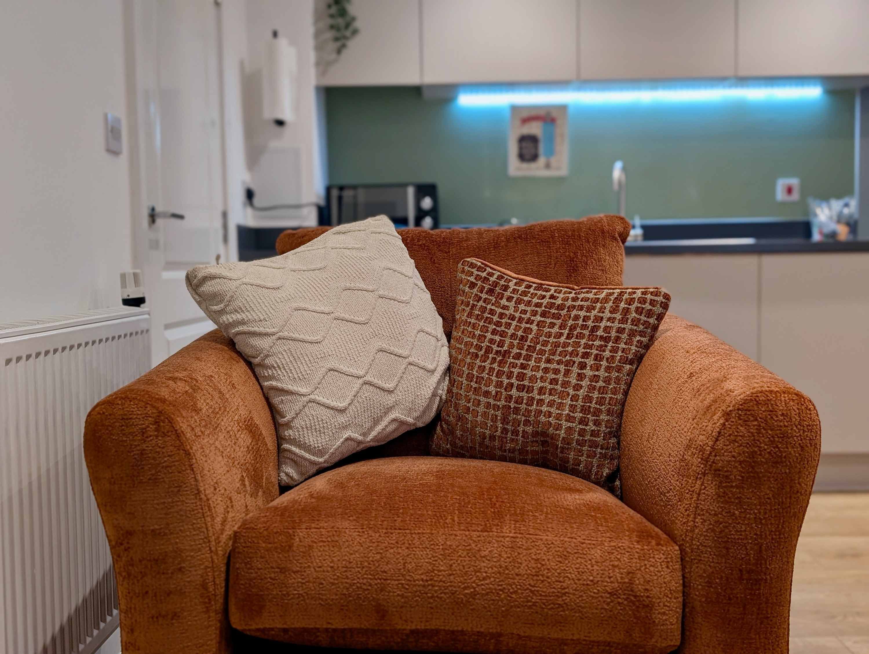 A brown sofa with two pillows in a modern kitchen setting.