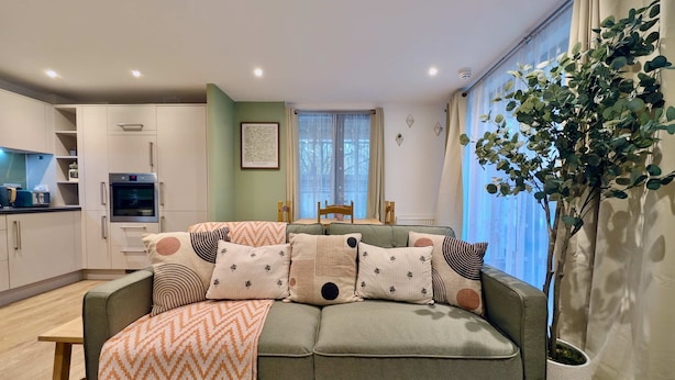 En moderne stue med sofa, spisebord og et køkkenområde.