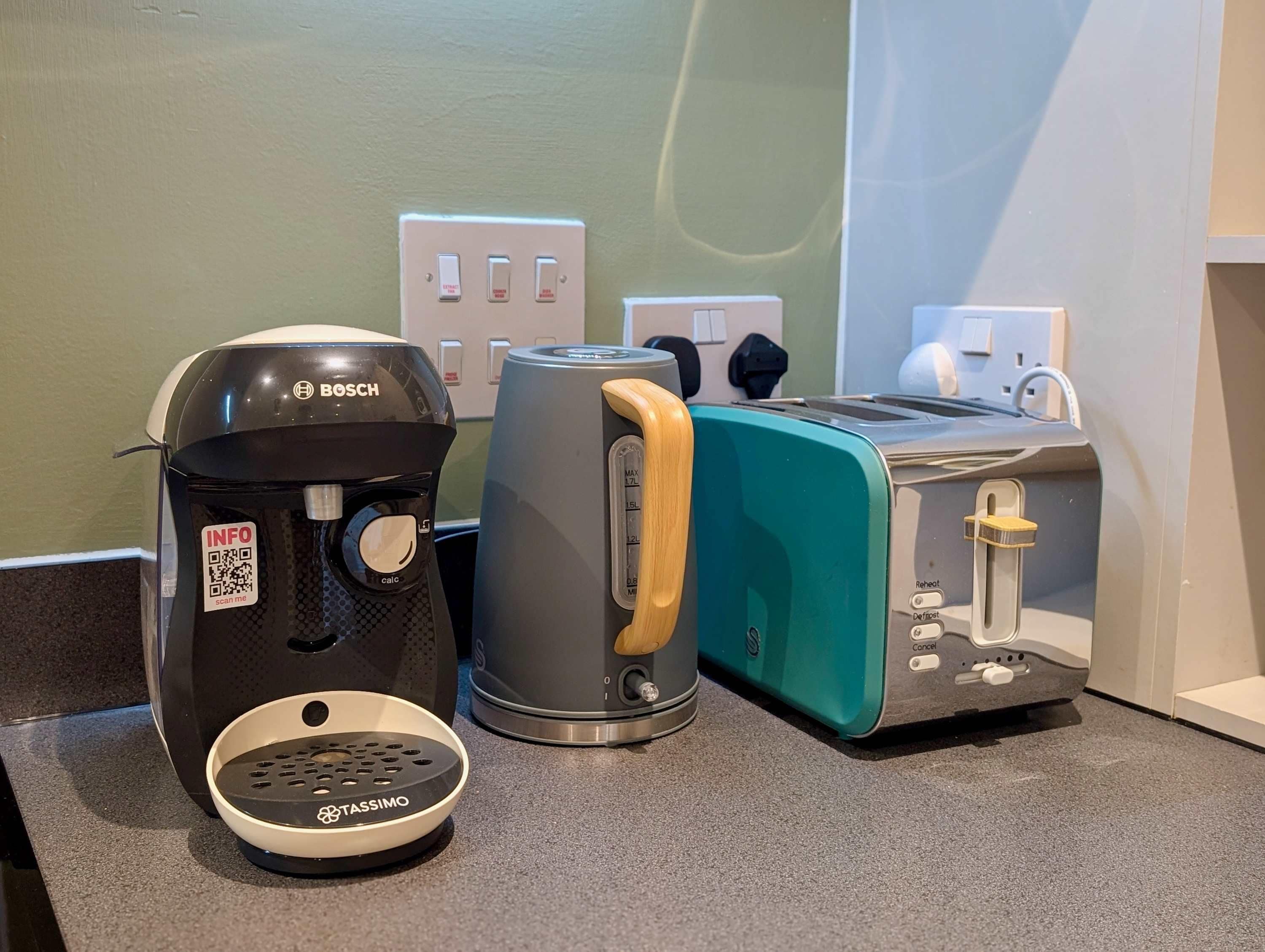 A coffee maker, a toaster, and a kettle on a kitchen counter.