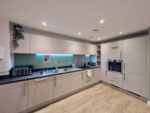 Une cuisine moderne avec des meubles de couleur claire, un évier en acier inoxydable, un four encastré et un four à micro-ondes.