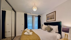 Et hotelværelse med en seng, et natbord, en lampe, et maleri og udsigt ud