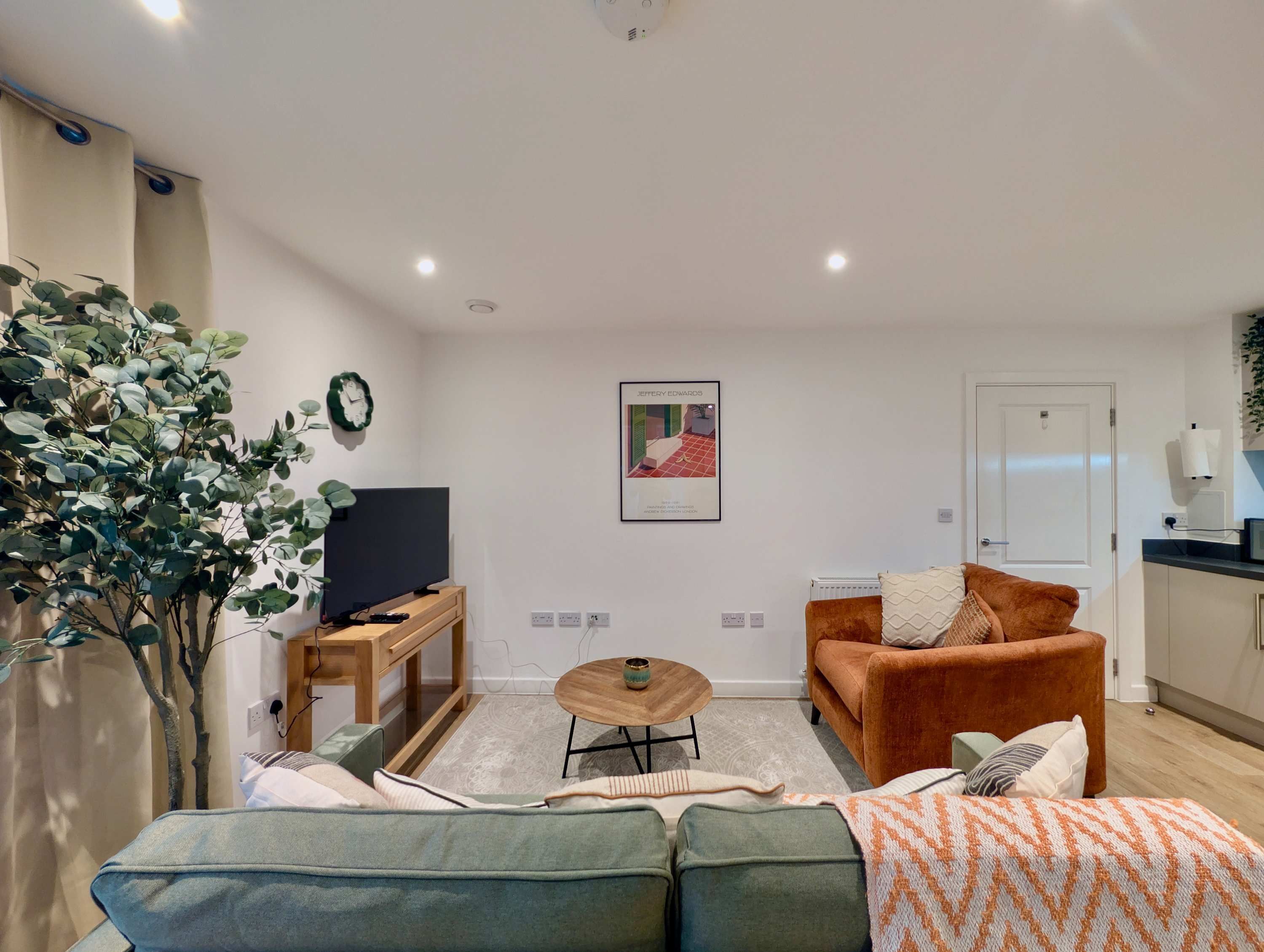 Una sala de estar moderna con un sofá, una mesa de centro, un televisor y una planta.