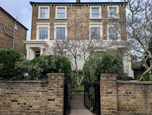 A two-story brick building with a central entrance flanked by brick walls and a black metal gate. - Victoria Park Retreat Stylish 2 Bed Flat (London)