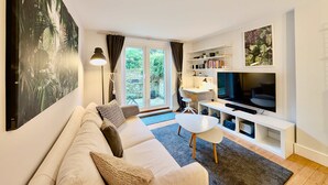 A modern living room with a sofa, TV, and a desk area. - Victoria Park Retreat Stylish 2 Bed Flat (London)