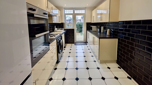 Cozinha moderna com ilha central, piso em ladrilhos preto e branco e vista para o exterior.