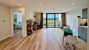 A modern apartment with a dining area, kitchen, and a balcony with a view. - Amazing Flat With Free Parking and Balcony (Woking)