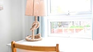 A lamp with a rope base on a white table near a window. - Spacious 5-bedroom Family Home in Greenwhich (London)