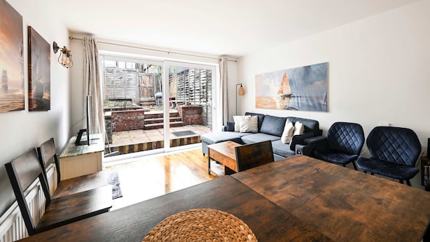 A modern living room with a sofa, chairs, a dining table, and artwork on the walls. - Spacious 5-bedroom Family Home in Greenwhich (London)