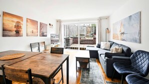 A modern living room with a dining area, large windows, and nautical-themed artwork. - Spacious 5-bedroom Family Home in Greenwhich (London)