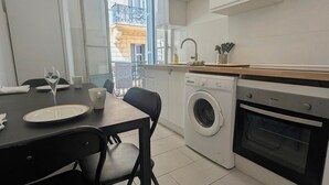 Een praktische keuken met een wasmachine, oven en een eethoek met stoelen en een tafel.
