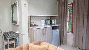 A compact living space with a kitchenette, a dining area, and a seating area. - Rhino Creek Estate (Bloemfontein)