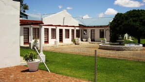 A white building with a red roof and columns, a paved courtyard, and a fountain. - Rhino Creek Estate (Bloemfontein)