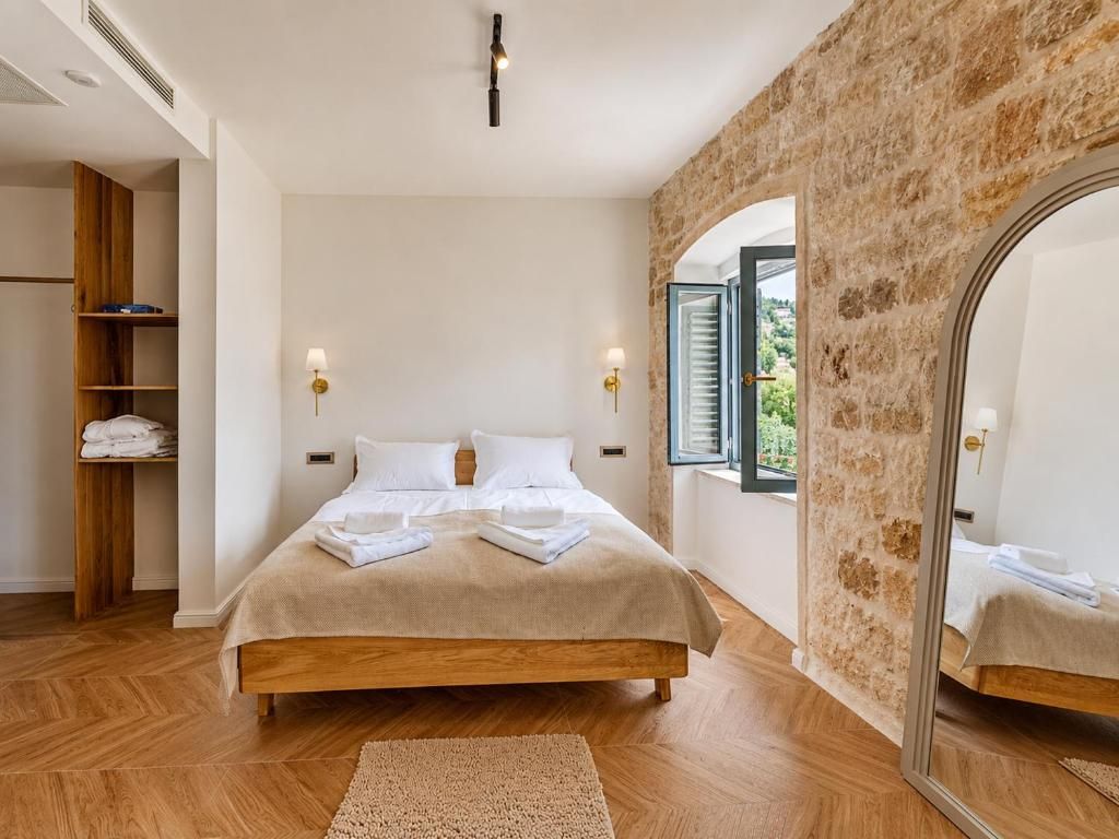 Ein Schlafzimmer mit einem hölzernen Bett, einem Spiegel und einer Steinwand.