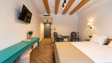 A hotel room with a bed, a desk with a chair, a television, and a small table with chairs.