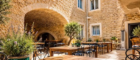 An outdoor dining area with stone walls, wooden tables, and chairs.