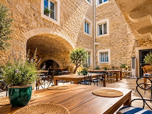 Un área de comedor al aire libre con paredes de piedra, mesas y sillas de madera.