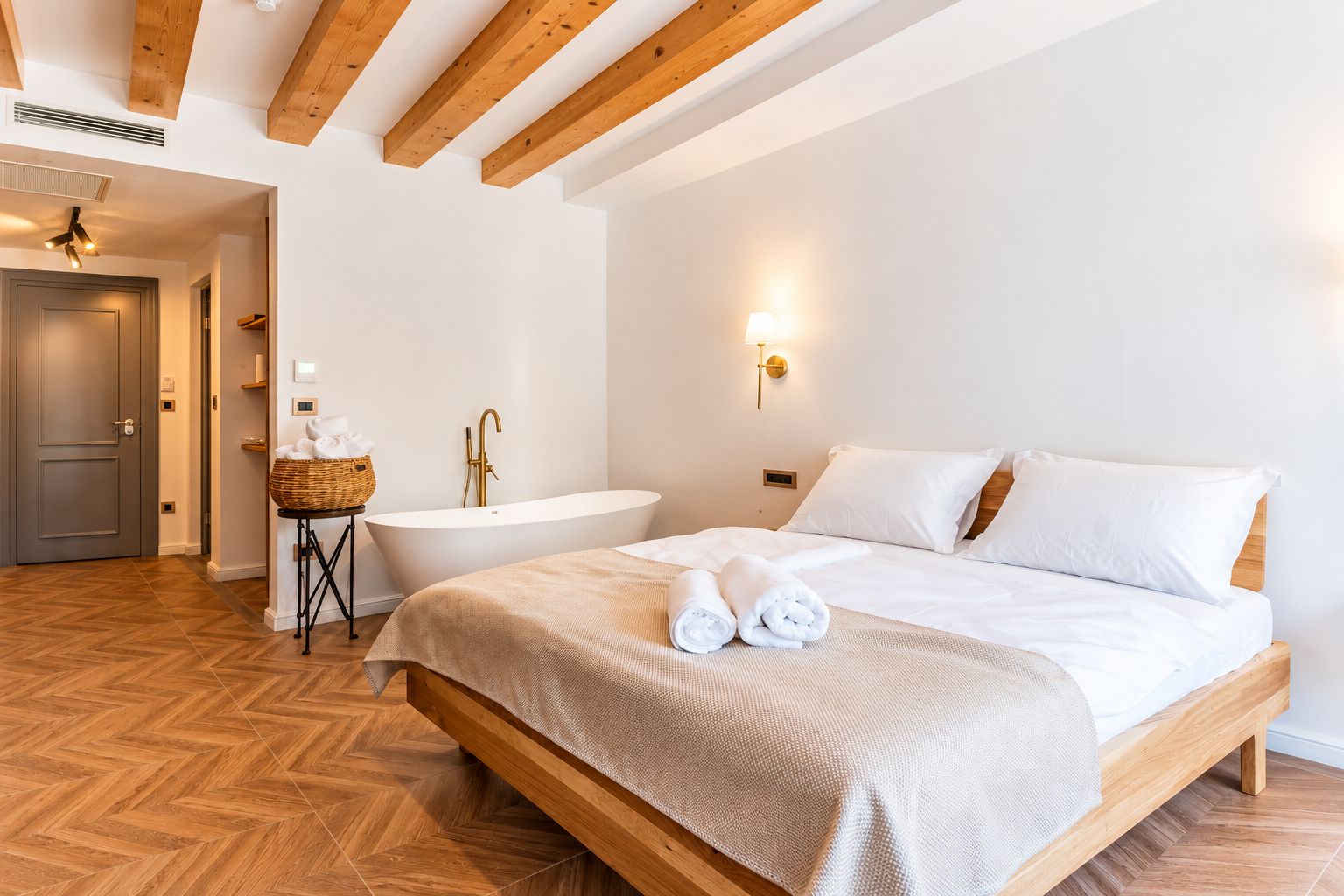 Una habitación de hotel con una cama grande, una bañera y suelo de madera.