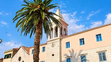 A building with a clock tower, palm trees, and a clear blue sky.